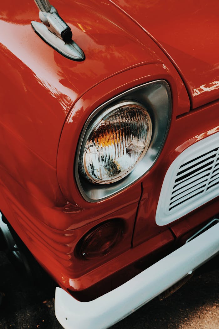 Detail of a classic red car's headlight showcasing vintage design in Ankara, Turkey.